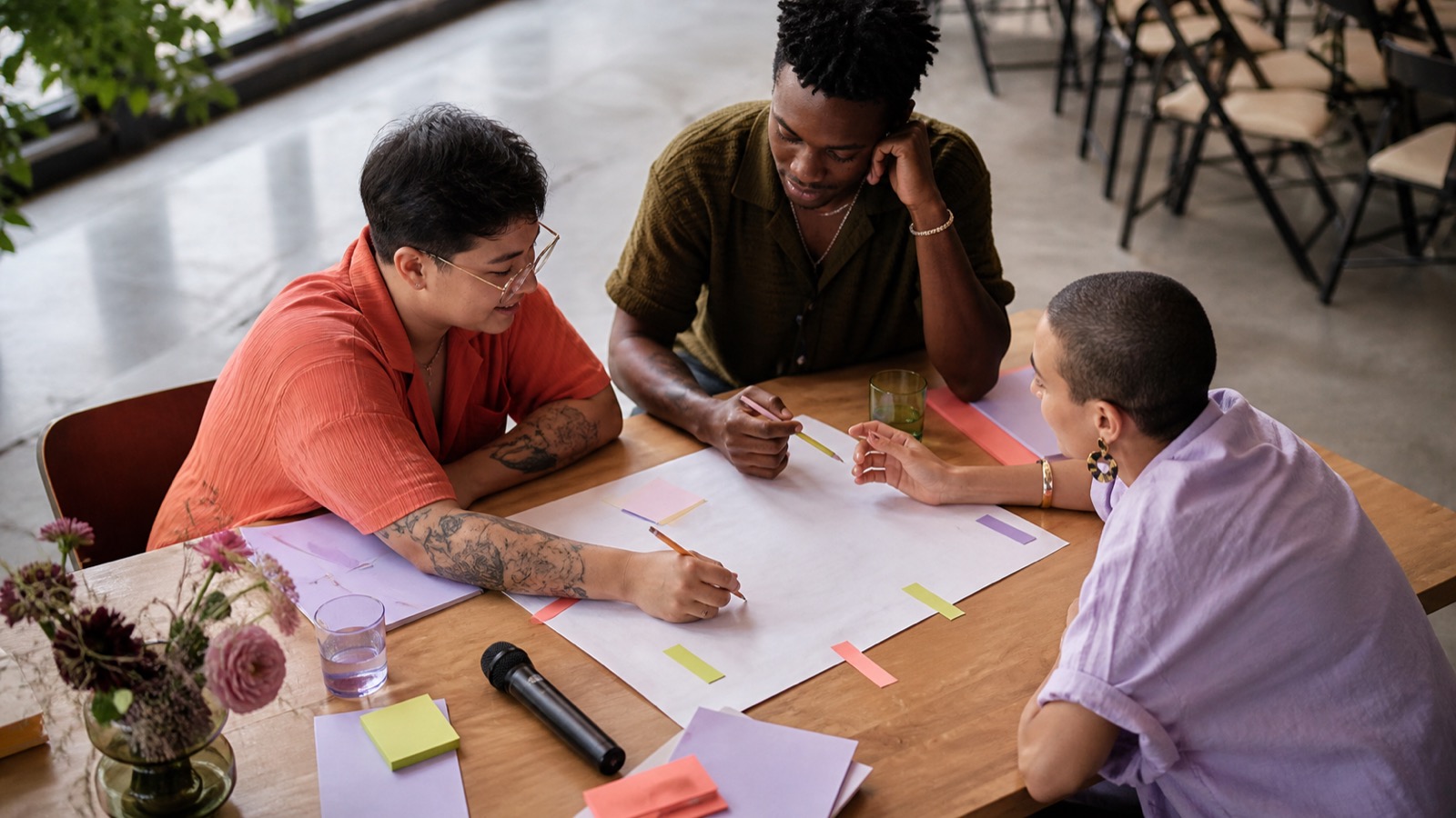 Three people collaboratively planning a ceremony with a microphone and colored cue tabs